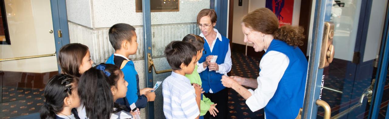 Volunteer ushers greeting a group of children